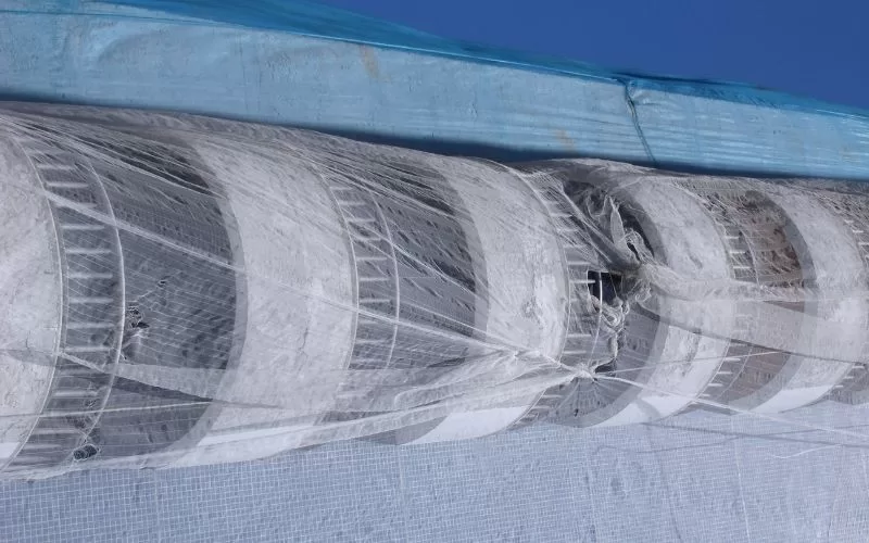 Tubo de concreto em construção coberto com rede azul.