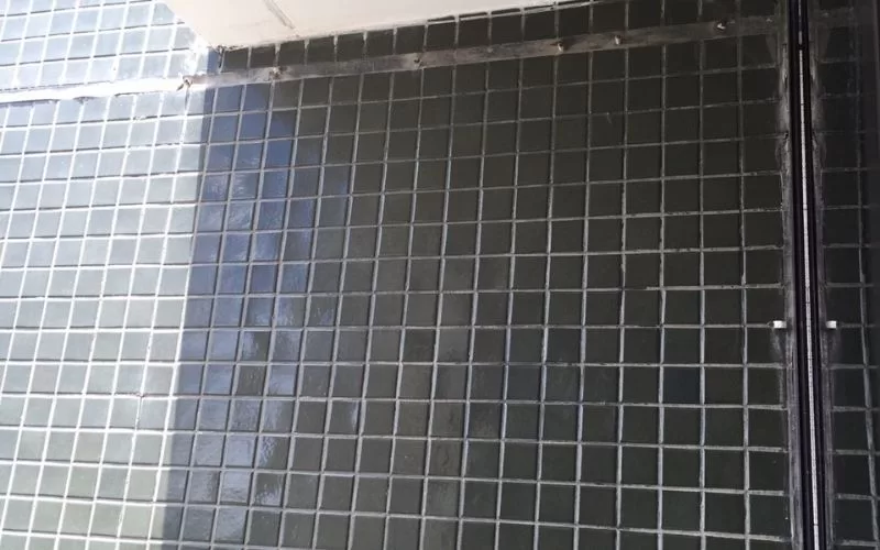 Parede revestida com azulejos pretos em mosaico.