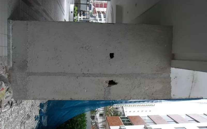 Pilar de cimento em construção, coberto parcialmente.