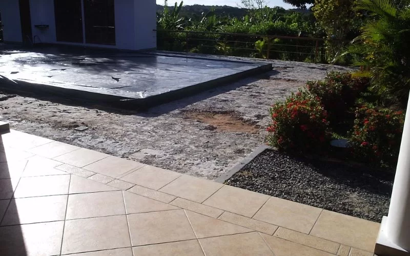 Piscina coberta em quintal com flores e árvores.