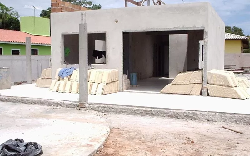 Construção de casa em fase inicial com materiais empilhados.