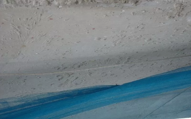 Parede de reboco com rede azul no canto.