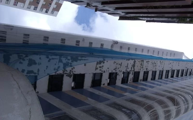 Prédio em construção com fachada coberta por rede azul.