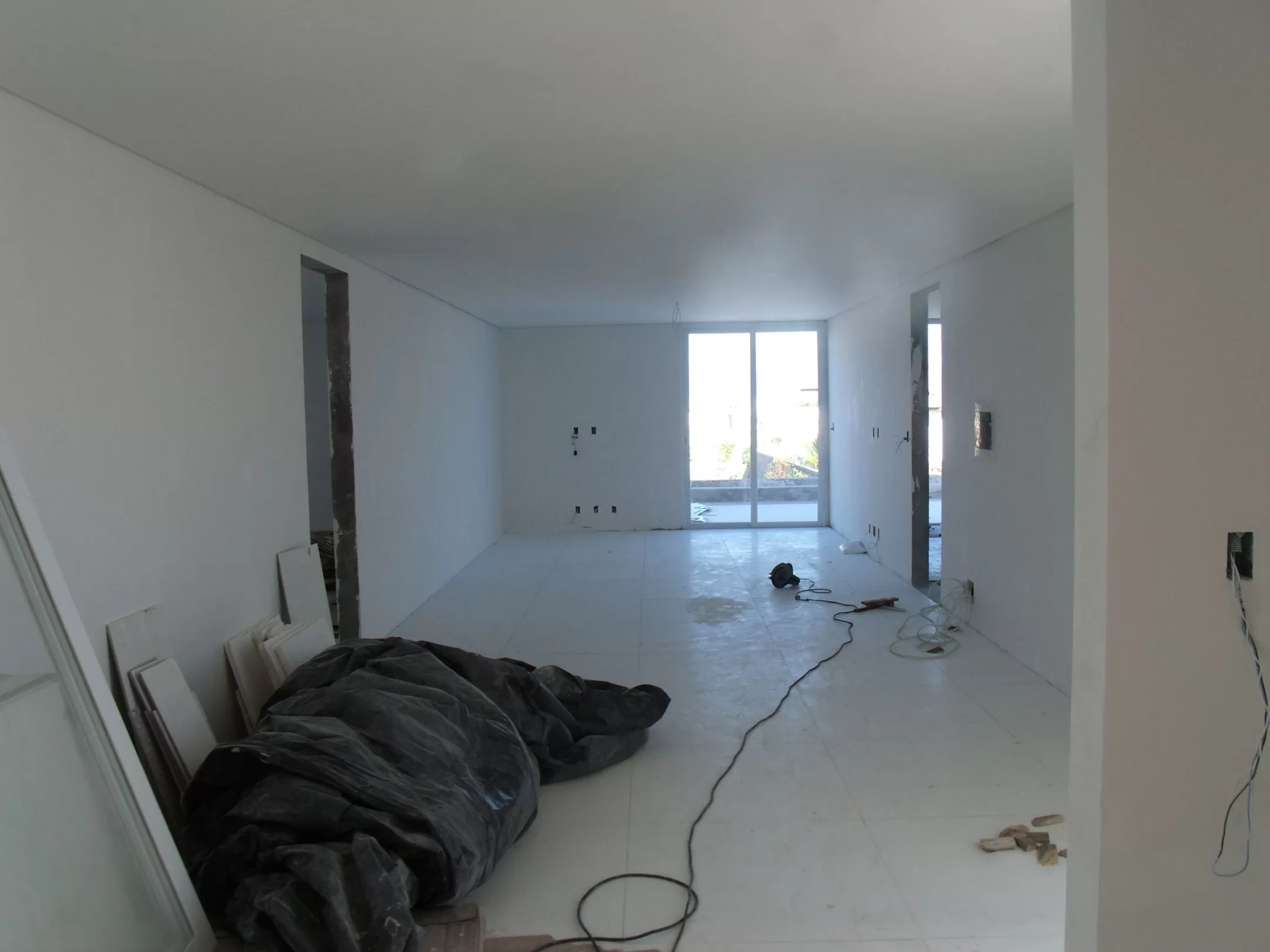 Sala ampla em reforma, janelas ao fundo.