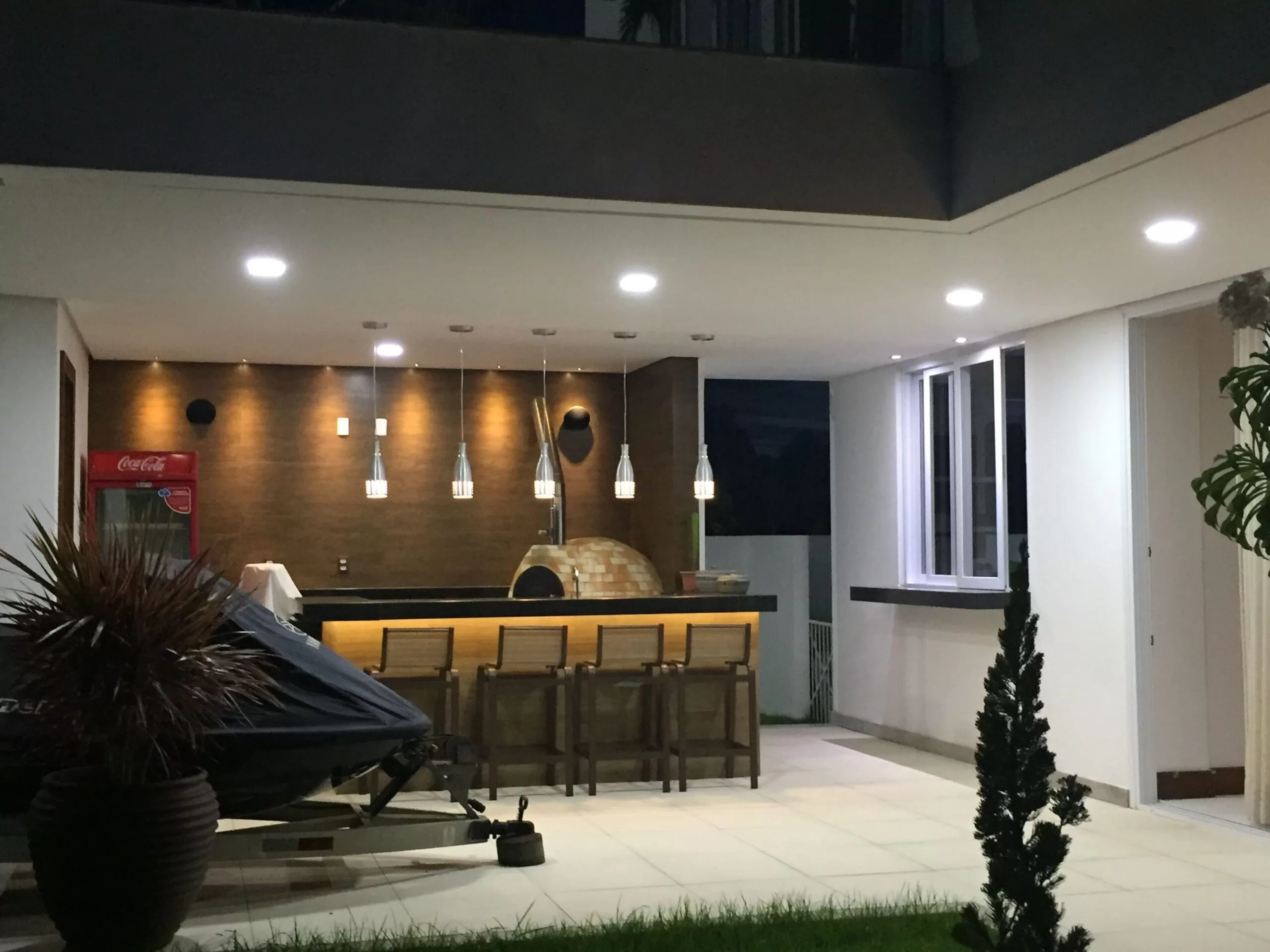 Área externa com bar e forno a lenha iluminados