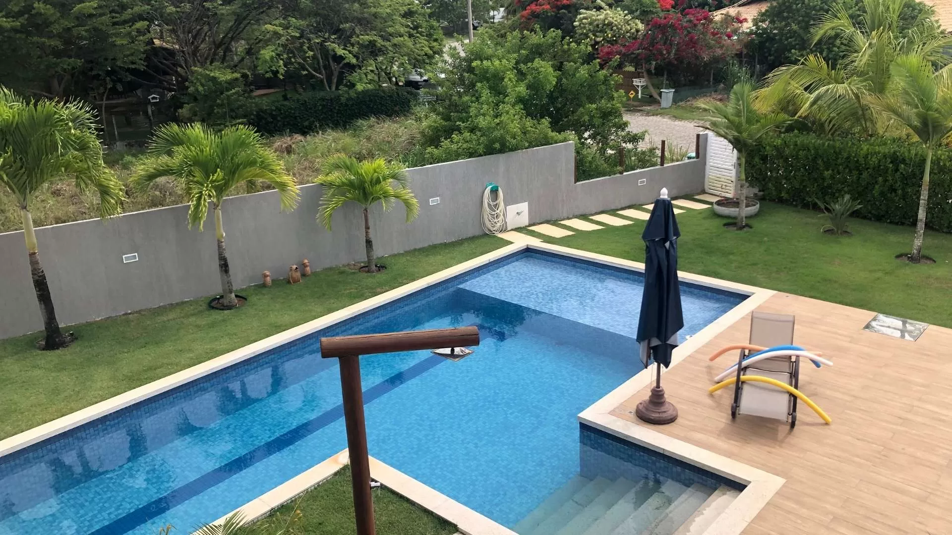 Piscina moderna com espreguiçadeira e guarda-sol