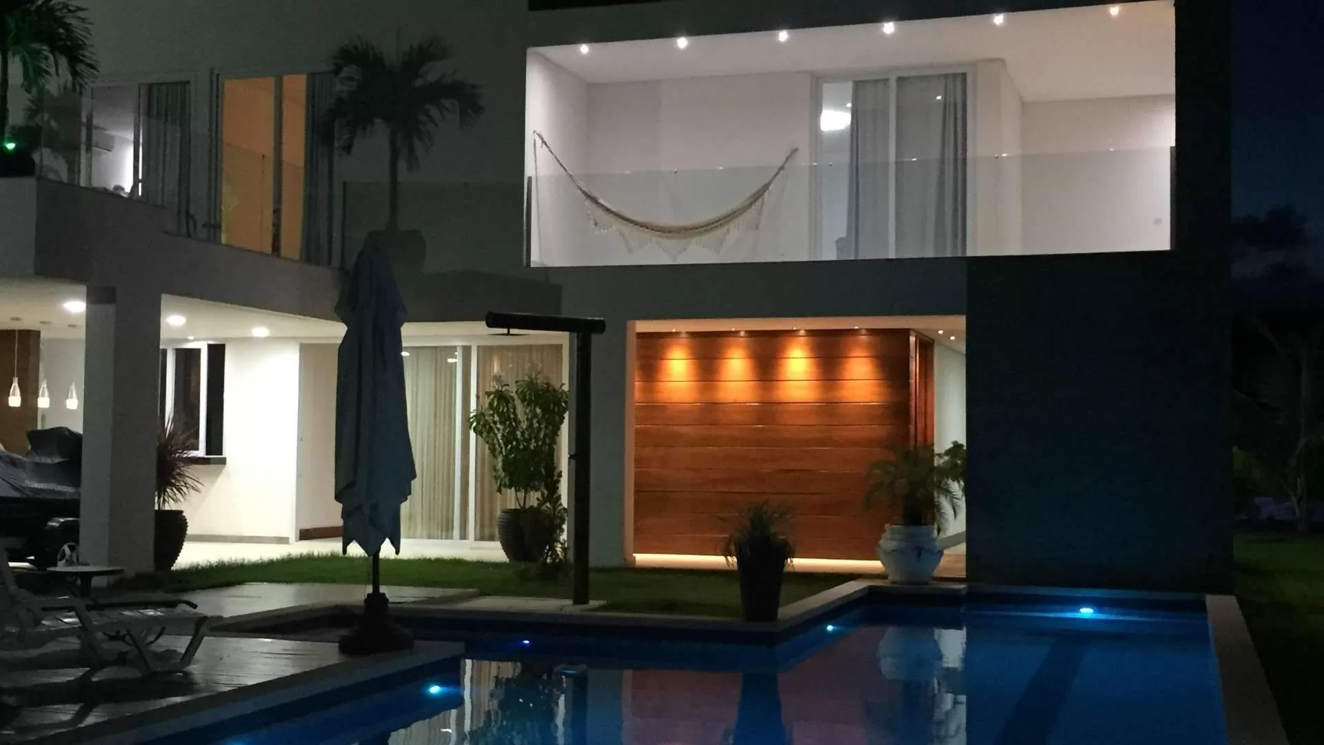 Casa moderna iluminada à noite com piscina.