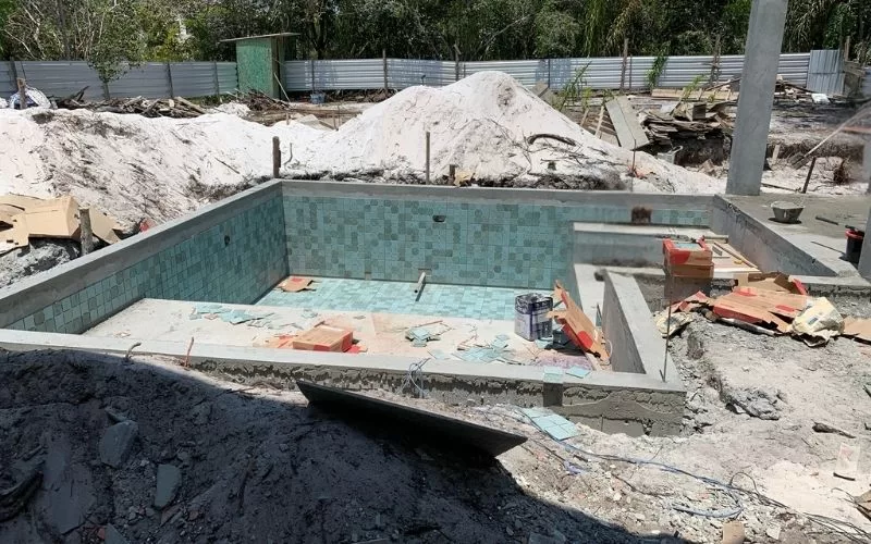 Construção de piscina com azulejos verdes.