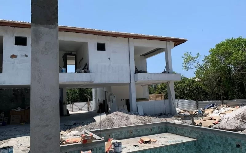 Casa em construção com piscina vazia.