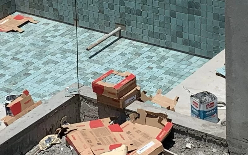Piscina em construção com materiais espalhados.