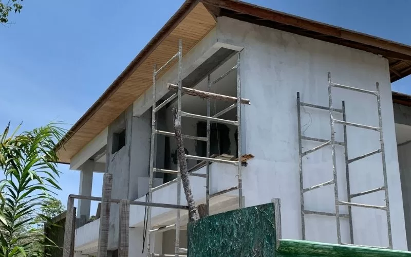 Casa em obras com andaimes ao redor.