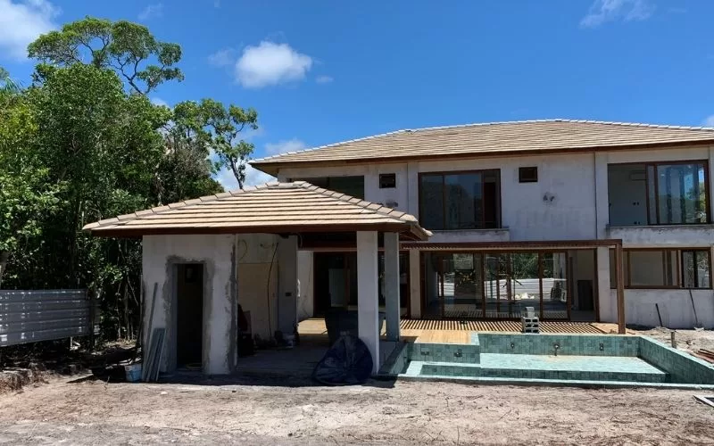 Casa em construção com árvores ao fundo.
