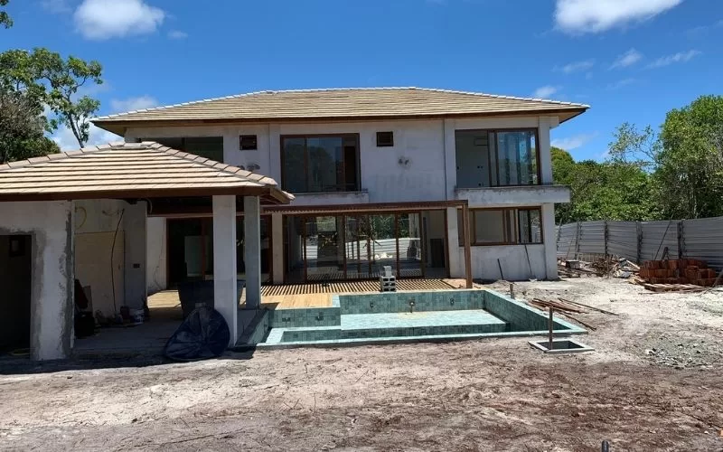 Casa moderna em construção com piscina inacabada.