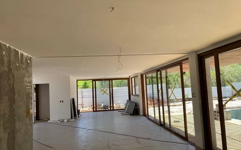 Sala em remodelação com janelas grandes de vidro.