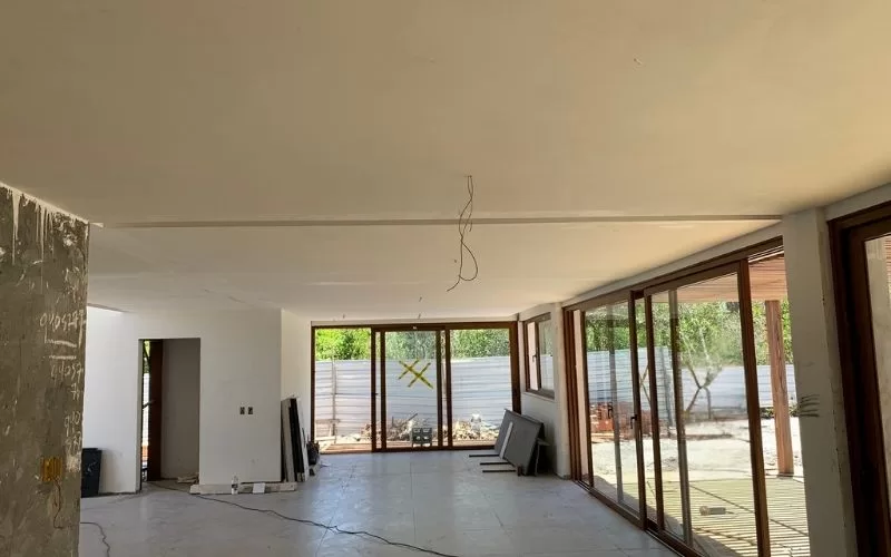 Sala ampla com janelas grandes em construção.