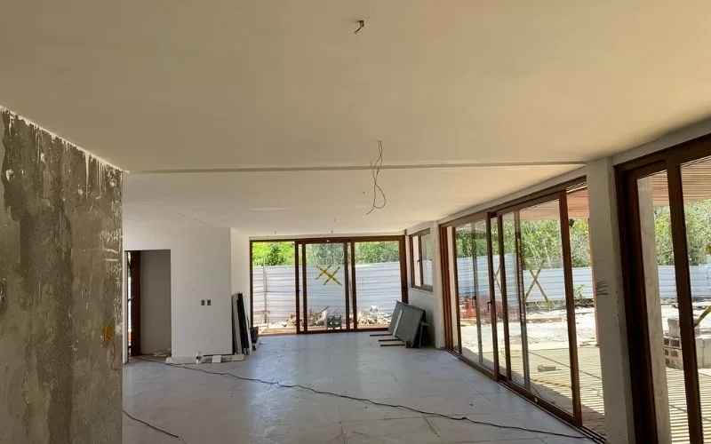 Sala ampla em construção com janelas grandes.