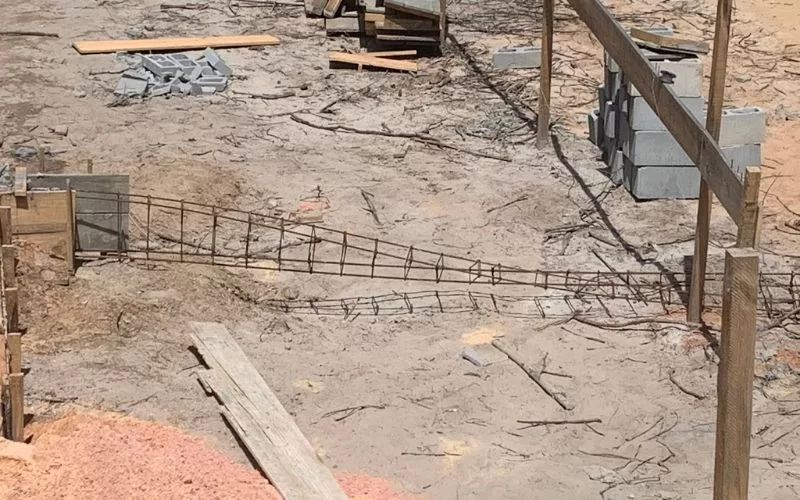 Construção com vergalhões e blocos de cimento empilhados.