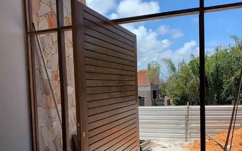 Porta de madeira aberta com vista para jardim.