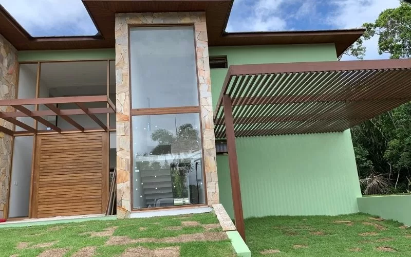 Fachada moderna de casa com vidro e pergolado.