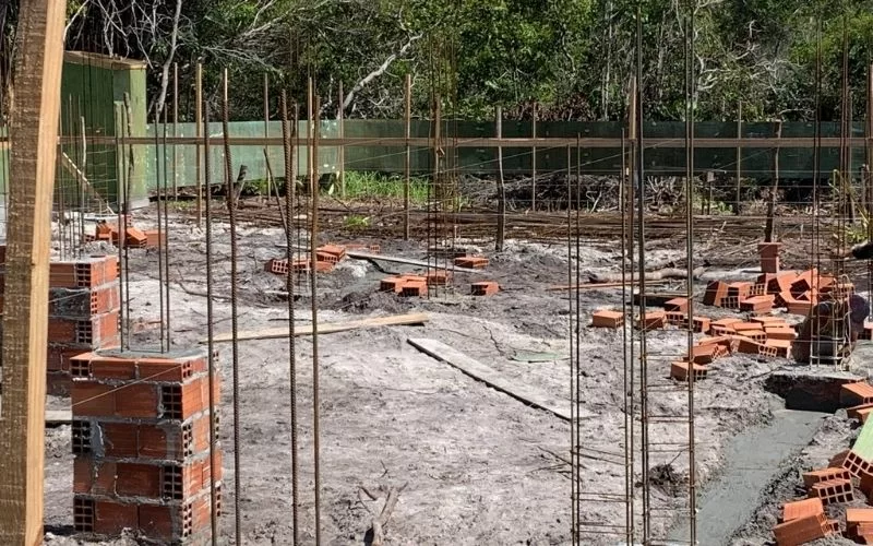 Construção com tijolos e vergalhões, fundação em andamento.