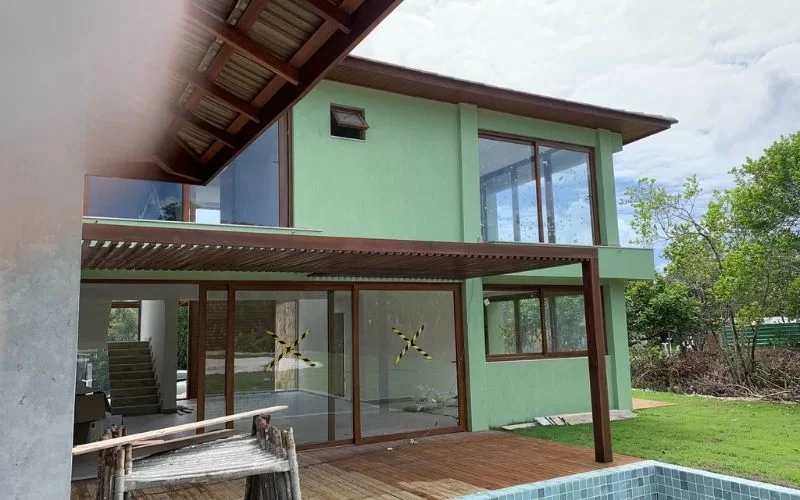 Casa moderna com janelas grandes e jardim verde.