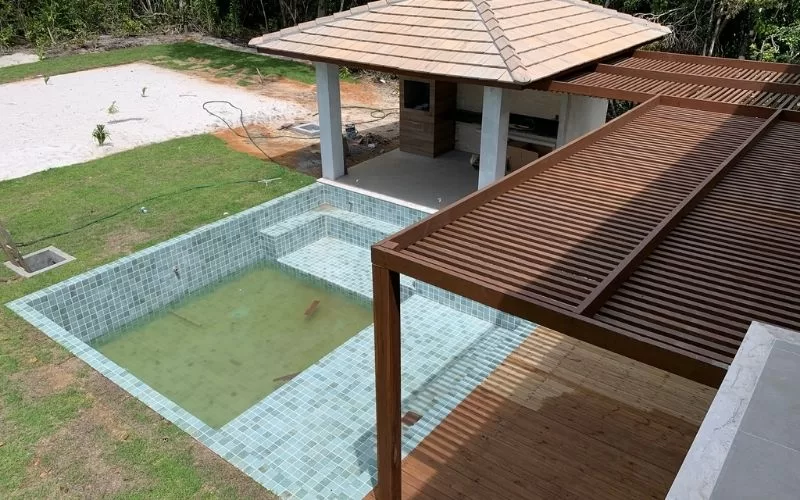 Piscina vazia com alpendre e terraço em madeira.