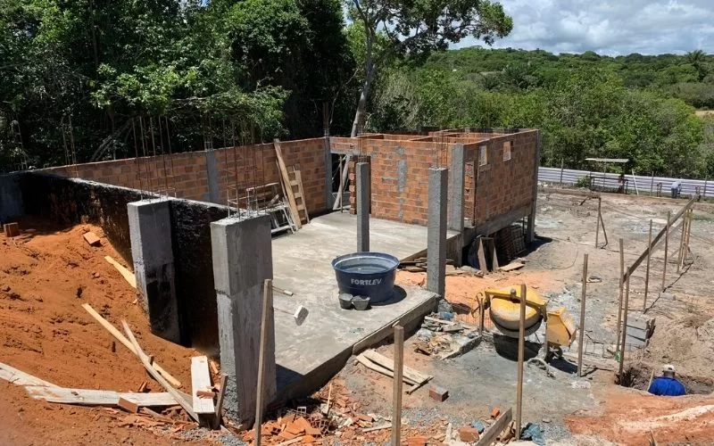 Construção de casa em processo, paredes de tijolo visíveis.