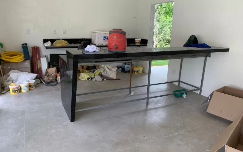 Espaço em construção com bancada e materiais variados.