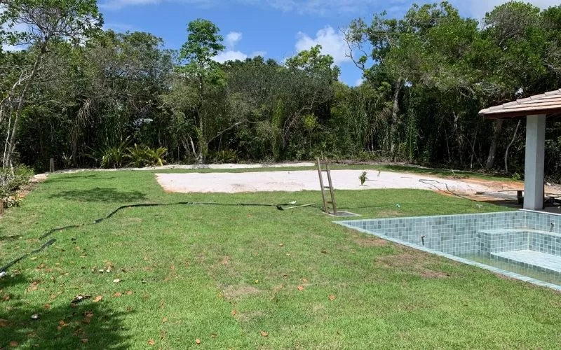 Quintal com piscina e área de jardim verde.