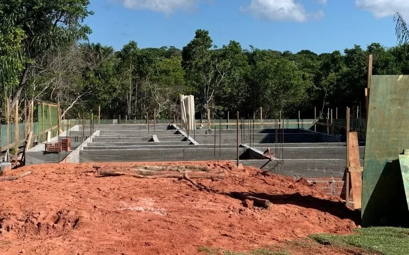 Construção de piscina em betão numa área arborizada.