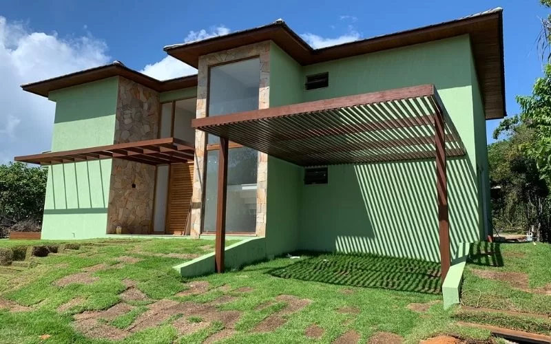 Casa moderna com fachada de pedra e jardim verde.