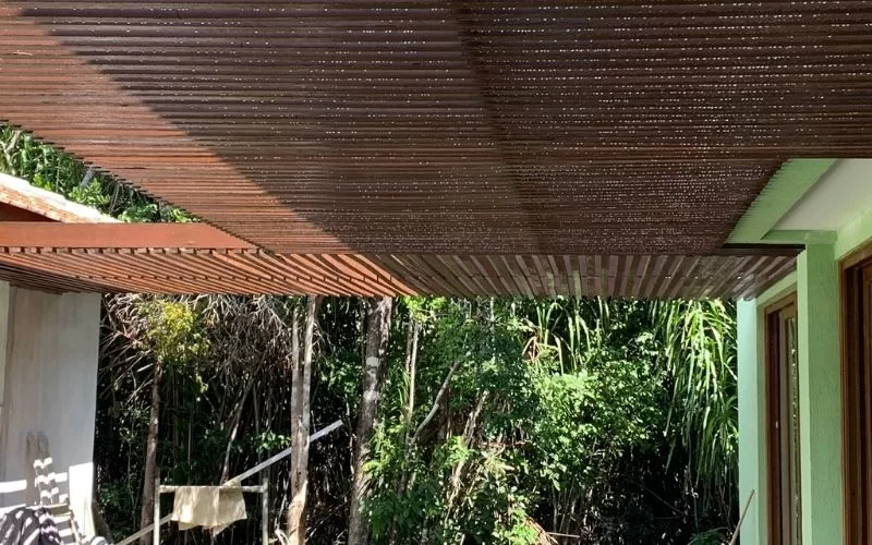 Pérgula de madeira com jardim ao fundo.