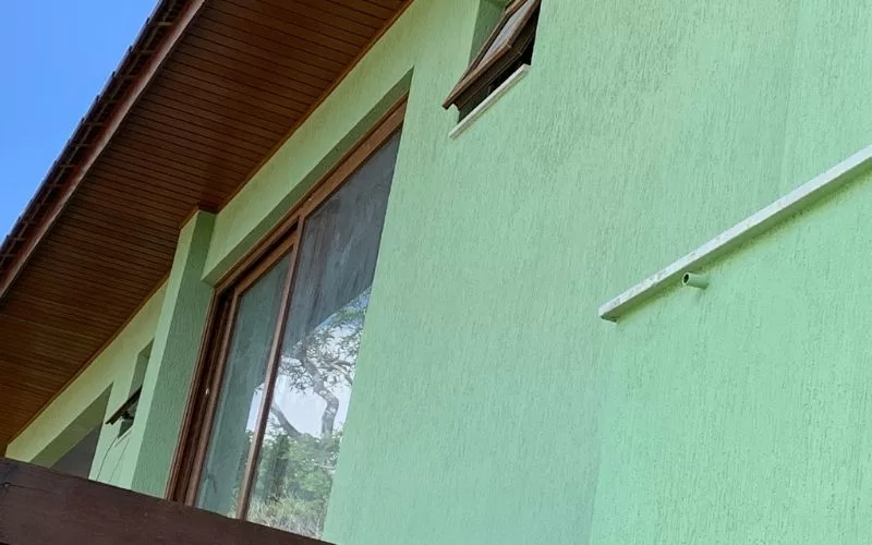 Fachada de casa verde com janelas de madeira.