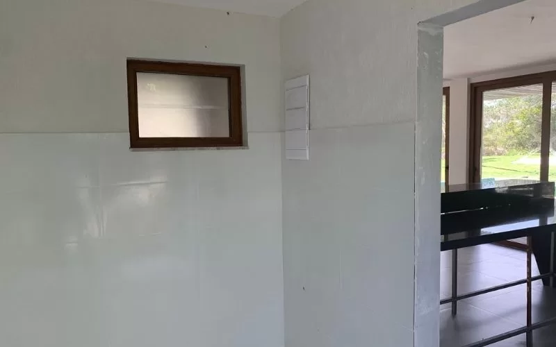 Cozinha vazia com janelas grandes ao fundo.