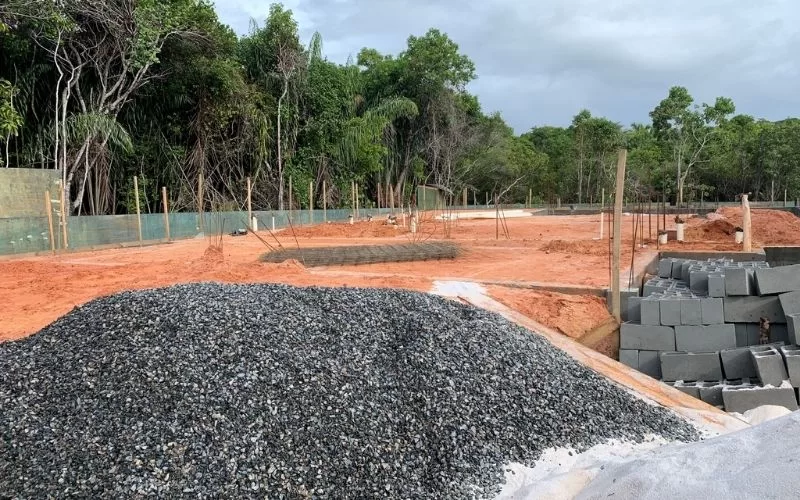 Terreno em construção com árvores e materiais de construção.