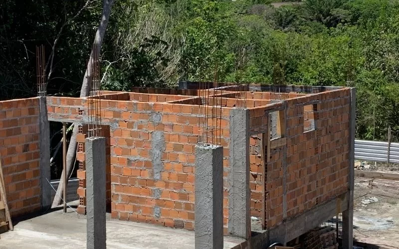 Casa em construção com tijolos aparentes.