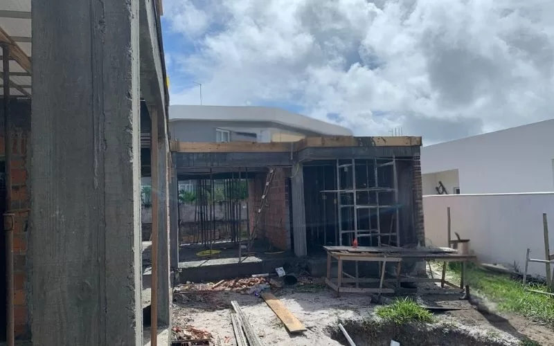 Construção de casa com céu nublado ao fundo.