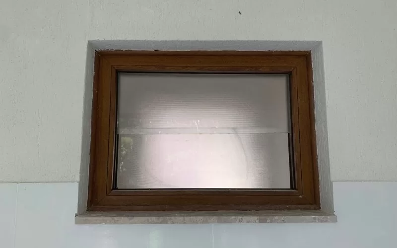 Janela retangular com moldura de madeira.