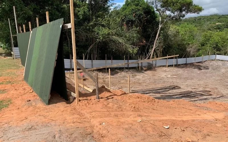 Terreno com vedação de metal na floresta.