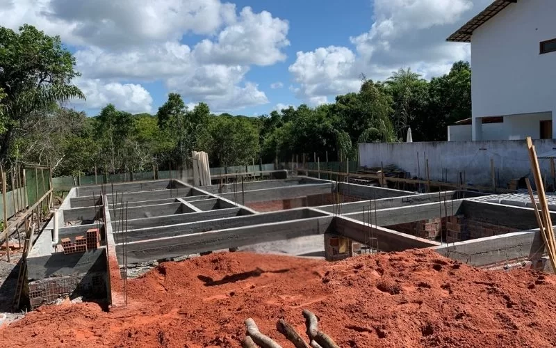 Construção de fundação em terreno com árvores ao redor.