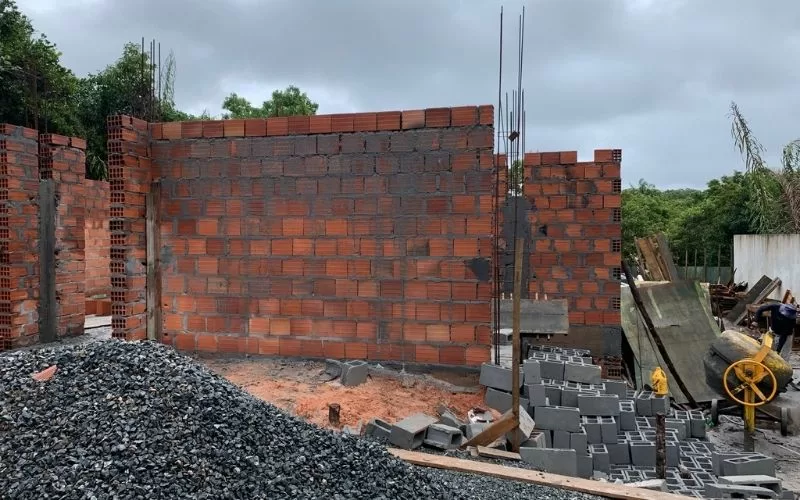 Parede de tijolos em construção sob céu nublado.