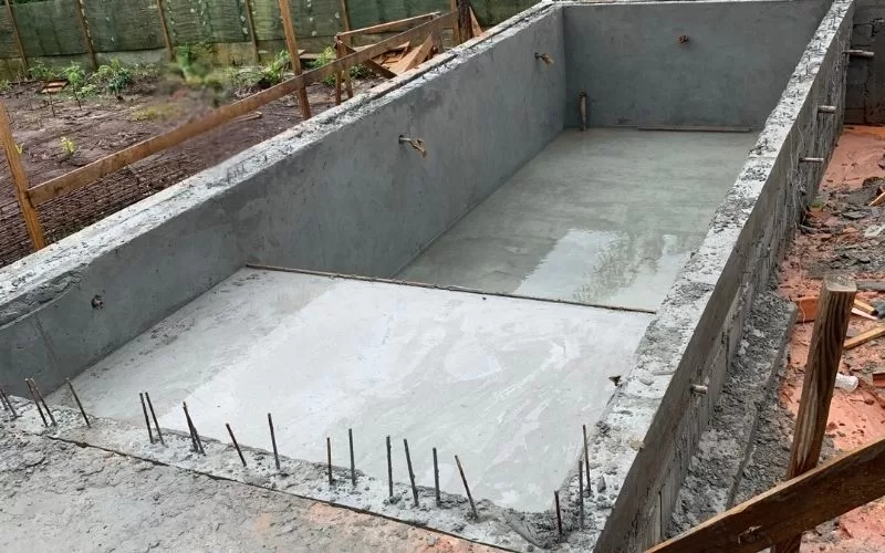 Piscina retangular em construção com base de cimento.