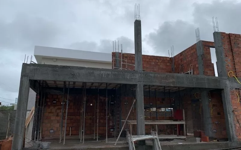 Casa em construção com tijolos visíveis e colunas.
