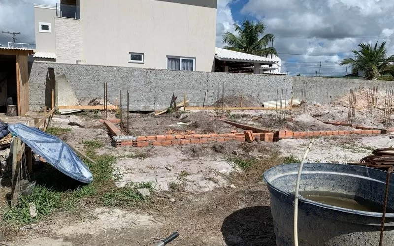 Construção de muro com tijolos em terreno arenoso.