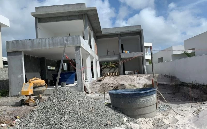 Construção de casa moderna em andamento, céu parcialmente nublado.