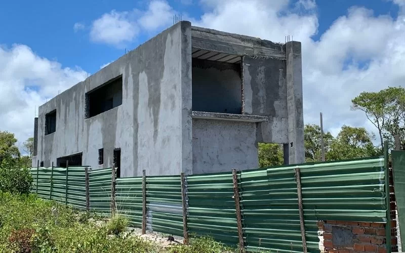 Construção inacabada cercada por vedação verde