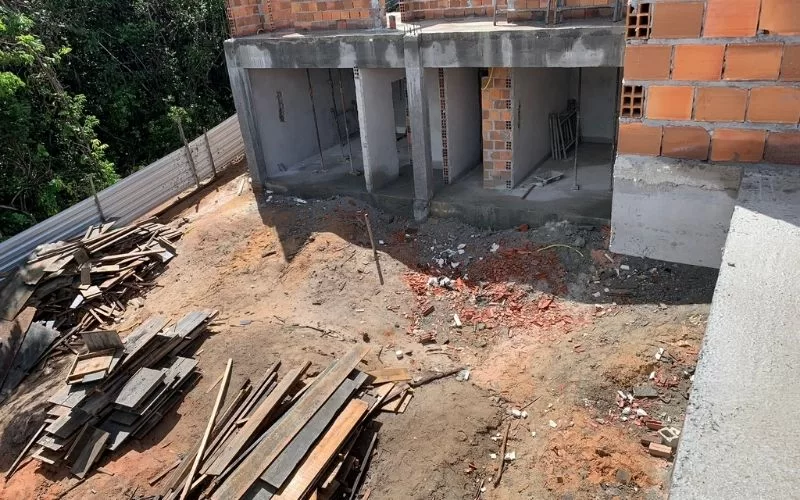 Obras de construção com tijolos e madeira empilhada.