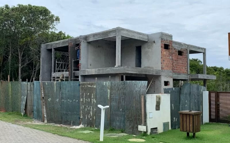 Casa em construção com andaimes e tapume
