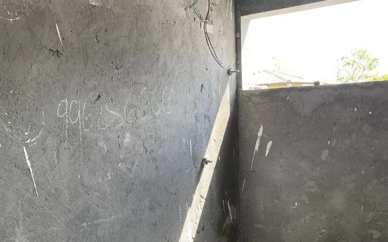 Parede de cimento com janela aberta e luz solar.