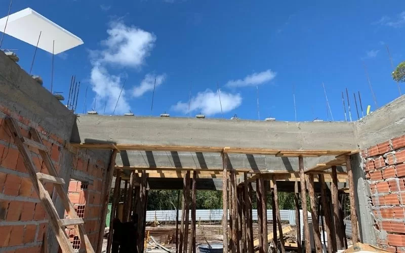 Obra em construção com paredes de tijolo e vigas.